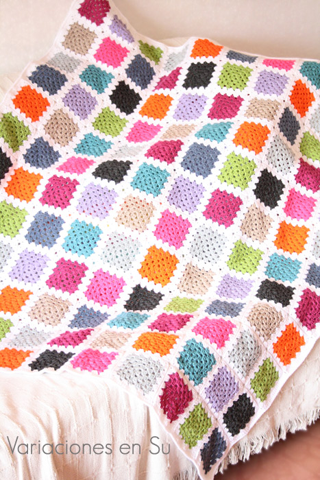 Manta de granny squares o cuadrados de ganchillo tejidos en lana de llamativos colores.
