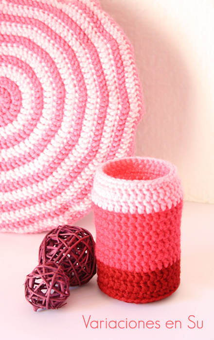 Funda de ganchillo para jarrón tejida en un degradado de tonos rosados.