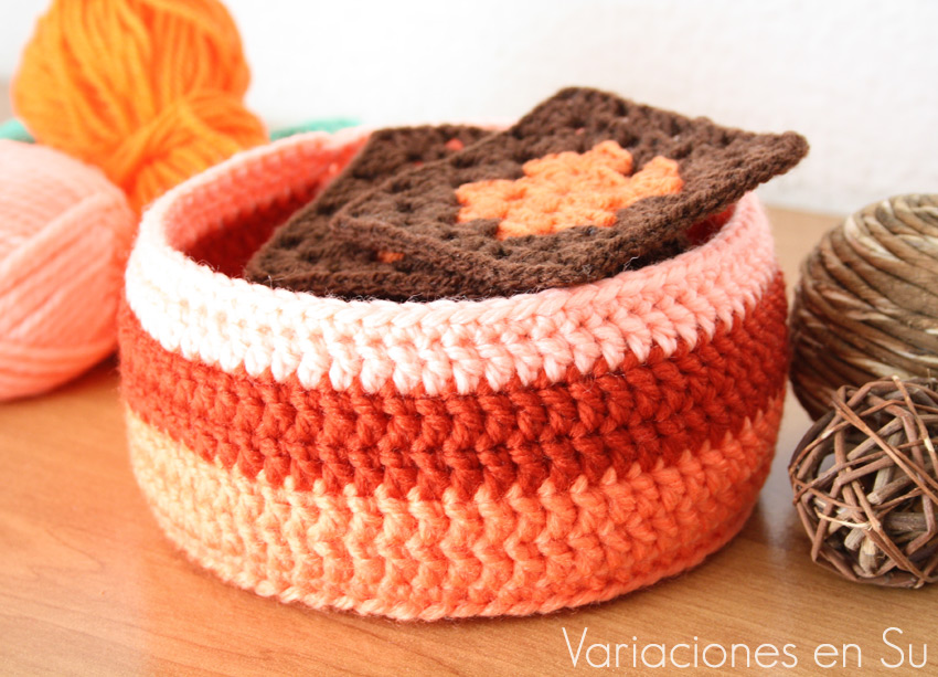 Cesta de ganchillo de forma circular, tejida en lana de tonos naranjas.