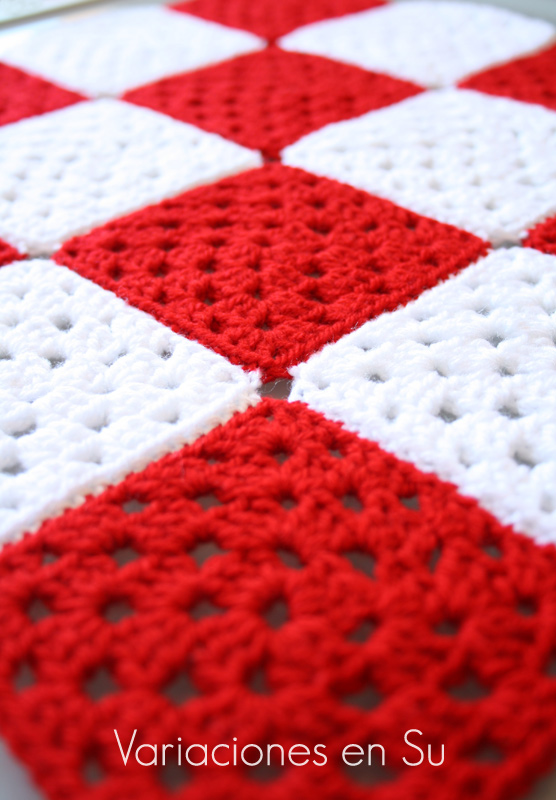 Granny squares o cuadrados de ganchillo tejidos en lana de colores rojo y blanco.