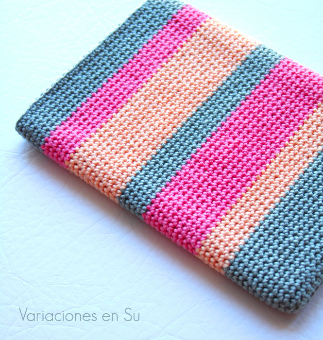 Funda de ganchillo para e-reader tejida con hilo de algodón en los colores gris, rosa y salmón.