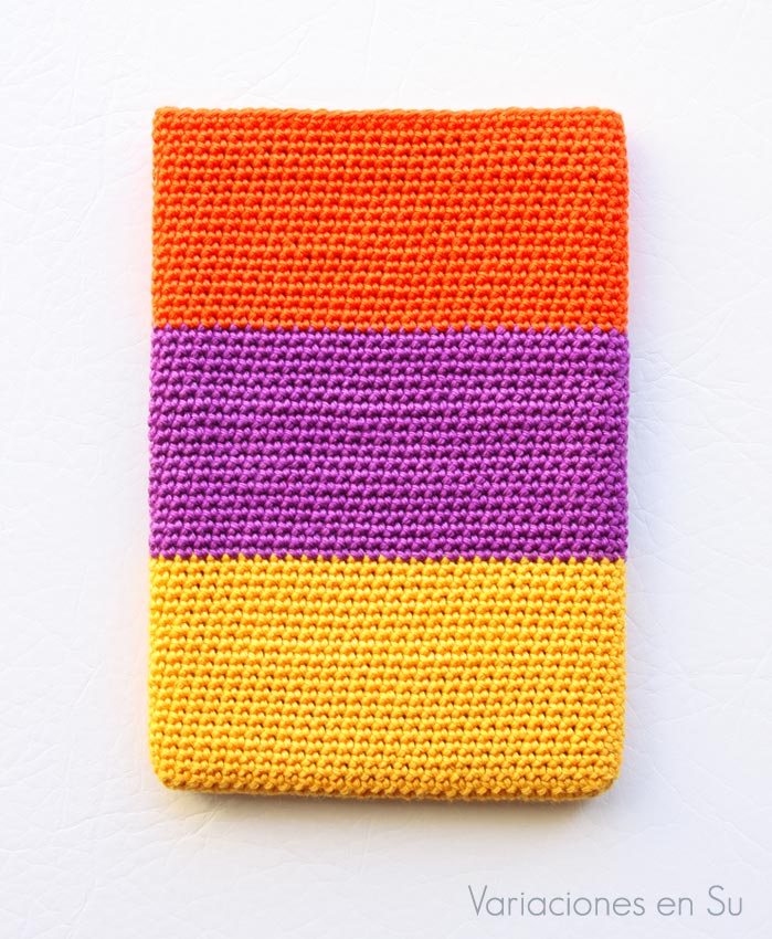 Funda de ganchillo para libro electrónico (e-reader) tejida en los colores naranja, violeta y amarillo.