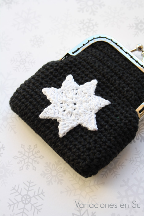 Monedero de ganchillo con estrella (detalle) Monedero de ganchillo en color negro con figura de estrella en blanco y boquilla plateada.