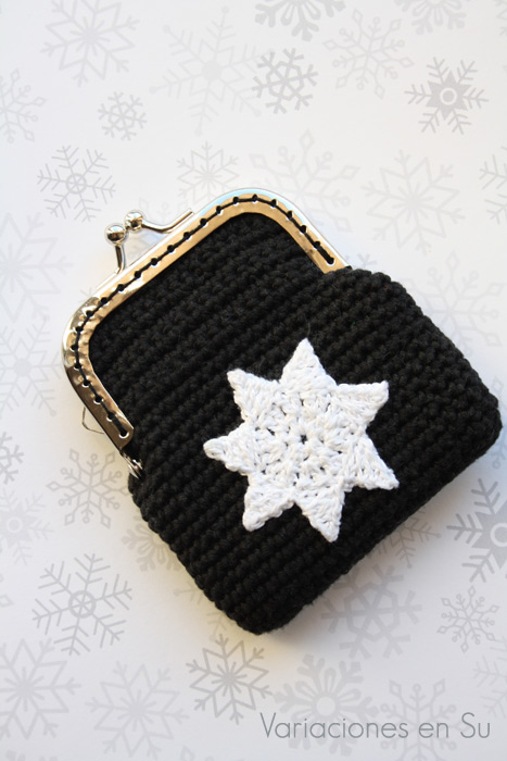 Monedero de ganchillo en color negro con figura de estrella en blanco y boquilla plateada.