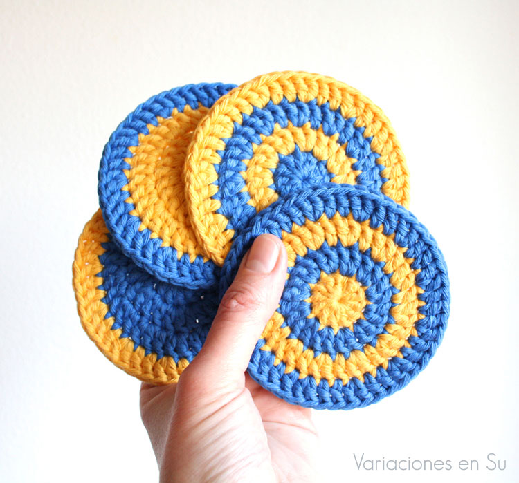 Set de cuatro posavasos de ganchillo tejidos en hilo de algodón en los colores amarillo y azul.