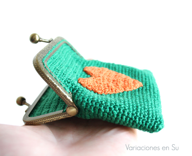 Monedero verde con corazón naranja (detalle) Monedero de ganchillo en color verde con figura de corazón en naranja y boquilla metálica de color bronce con filigrana.