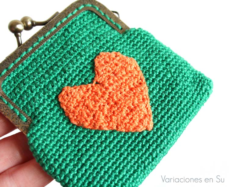 Monedero verde con corazón naranja (detalle) Monedero de ganchillo en color verde con figura de corazón en naranja y boquilla metálica de color bronce con filigrana.
