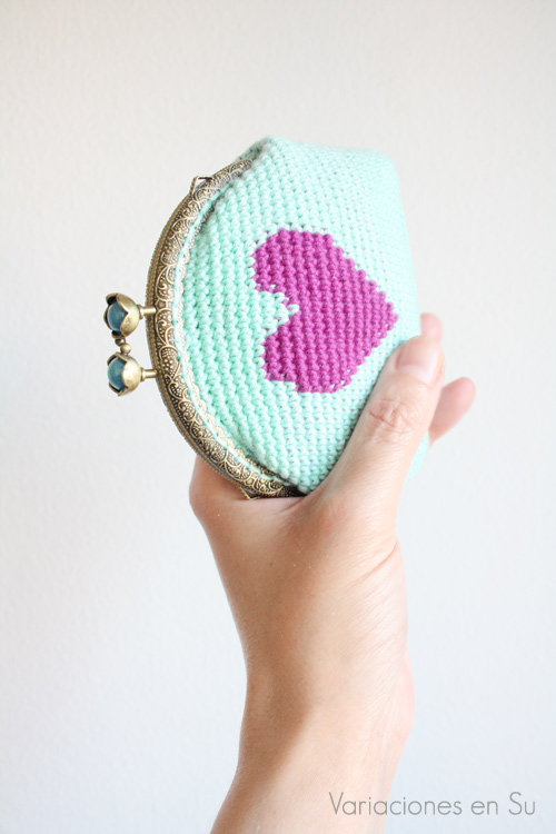 Monedero azul con corazón violeta Monedero de ganchillo en azul con figura de corazón en violeta. Está acabado con una boquilla metálica de color bronce con filigrana y cierre en forma de flor.