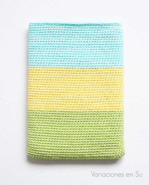 Funda de ganchillo para libro electrónico (e-reader) tejida con hilo de algodón en los colores verde, amarillo y azul. 