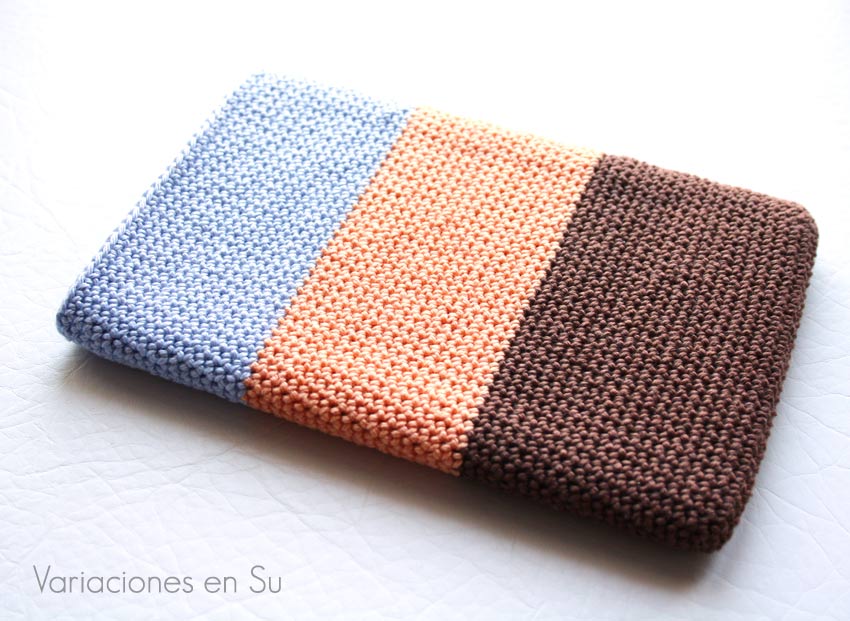 Funda de ganchillo para libro electrónico (e-reader) tejida con hilo de algodón en los colores marrón chocolate, salmón y azul celeste. 